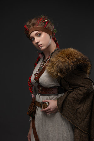 Fantasy Viking heroine holding Scandinavian axe in natural dress with fur cloakの写真素材