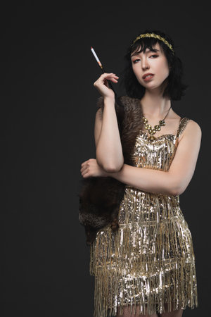 Art Deco beauty in golden flapper dress with pendant necklace and headband