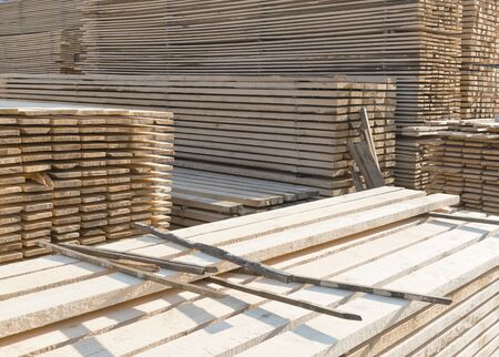 Piles of wooden boards in the sawmill, planking. Warehouse for sawing boards on a sawmill outdoors. Wood timber stack of wooden blanks construction material. Industryのeditorial素材