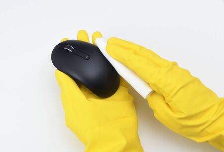 Disinfection in public places, the fight against the virus, coronavirus. A working hand wipes a computer mouse. A maid or housewife takes care of the house. Spring general or regular cleaning.の写真素材