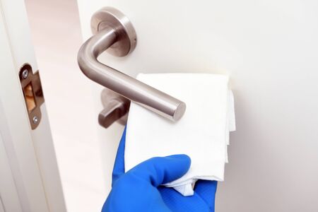 Disinfection in public places, the fight against the virus, coronavirus.Worker's hand wipes the door...