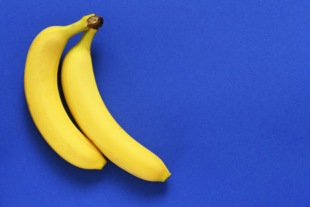 Yellow bananas on a blue background with place for text. Bright colors. Flat layの写真素材