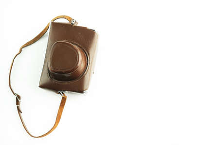 Top view of a small camera in a vintage brown leather case with shoulder strap isolated on a white...