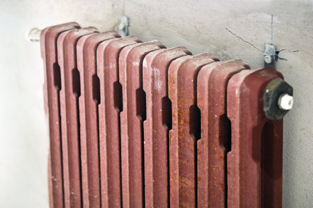 Rusty insulated mounted radiator on a rough brick wall plastered in an empty room of a newly built apartment or house.の写真素材