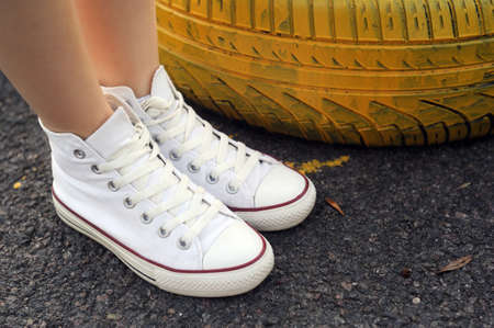 Belarus, Minsk - June 27, 2019: a girl in white cloth Converse sneakers stands on old car tires.