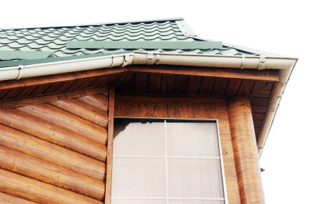 Roof made of metal with a gutter and a drainpipe. Log house with a roof made of iron tiles and a...