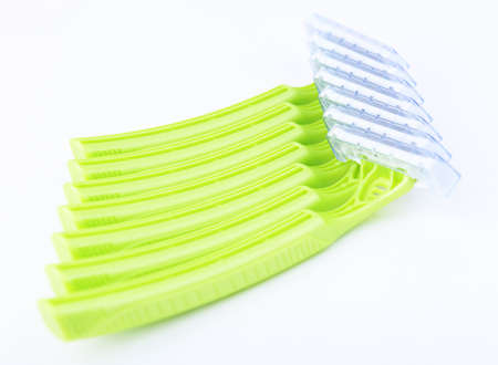 Disposable green plastic razor on a white background.Safe shaving with a sharp razor of female skin....