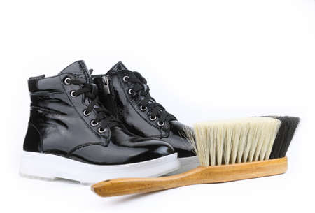 Care for patent leather. Shoe protection in rainy, wet weather. Female boot from black patent leather on a white sole, on a white background.の写真素材