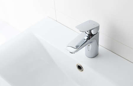 Modern faucet on white wall in bathroom, space for text