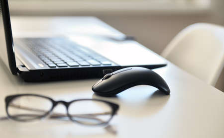 Close-up of computer mouse and eyeglasses on the tableの写真素材