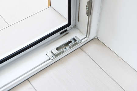 Close-up of a plastic window with a hinge and a door handle.