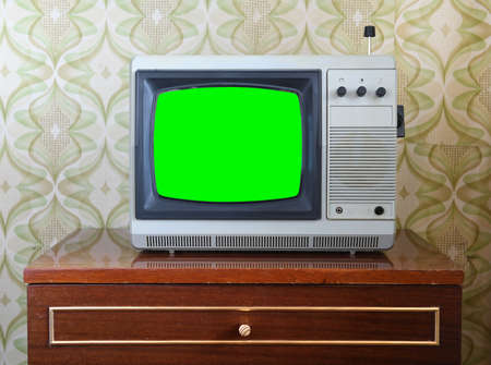 Retro television with green screen on wooden chest of drawers in roomの写真素材