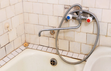 Dirt and mold in the old bathroom on the grout and tiles near the taps. Old plastic tiles on the walls.の写真素材