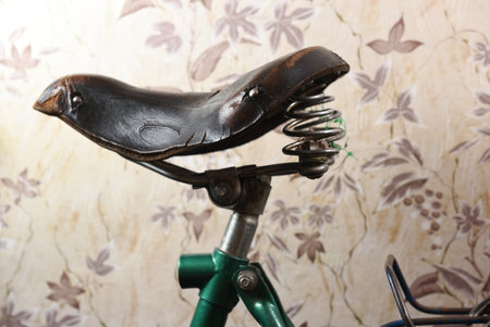 Old leather bicycle saddle against the background of old wallpaper in the apartment.の写真素材