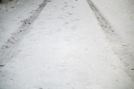 Tracks on a road covered in snowの写真素材
