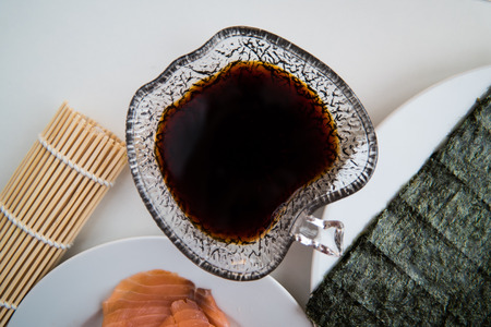 Soy sauce in a bowl with plates in the background ready for sushi.の写真素材