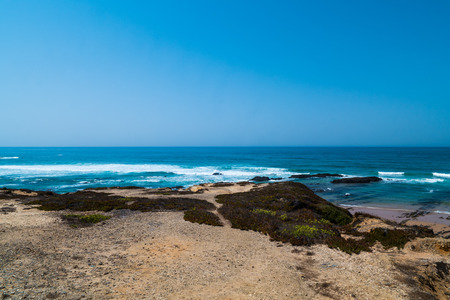 A view of the atlantic ocean from a beach showing cliffs and rocksの写真素材