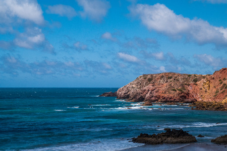 A portuguese beach in a bay surrounded by cliffs and the oceanの写真素材
