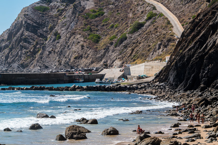 A road going up a cliff next to a beach in Portugalの写真素材