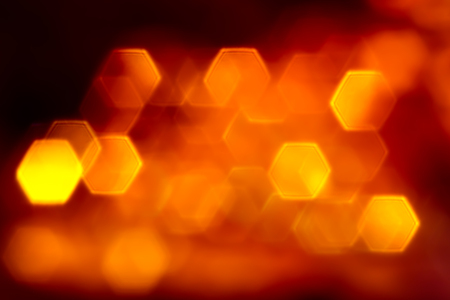 Bright orange flat hexagone lights bokeh on black backgroundの写真素材