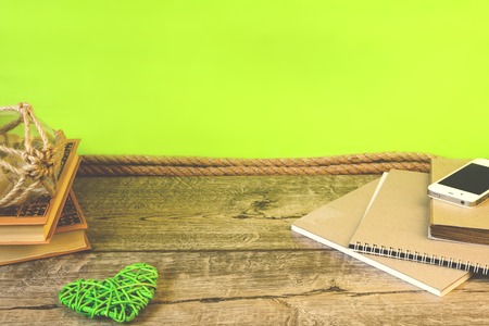 School notebooks, pencils and other items on green and wooden background