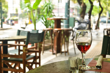 The glass of red wine standing on a table of street cafe, Athens, Greeceの写真素材