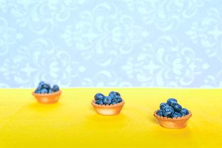 Blue berries in tartlets on a yellow backgroundの写真素材