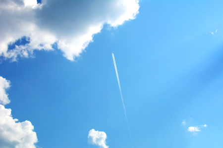 Trace from the plane in the background of blue sky with cumulus cloudsの写真素材