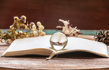 The transparent glass sphere lies on the opened notebook with a bookmarkの写真素材