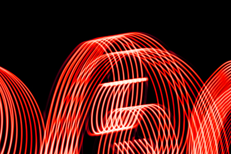 Bright red spiral patterns from light strips on a black backgroundの写真素材