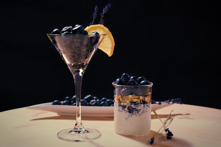 Coctail with bluberriy in martini glass on wooden table and black backgrounsの写真素材