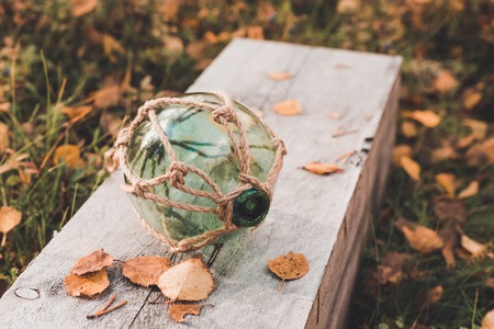 Big transparent glass sphere lies in a wooden board with pale leavesの写真素材