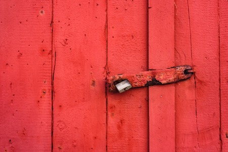 Big metallic lock hanging on a red painted door