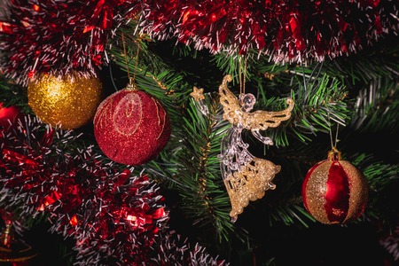 Close up big gold and red glitter ball and glass angel christmas on tree with wire white light backgroundの写真素材
