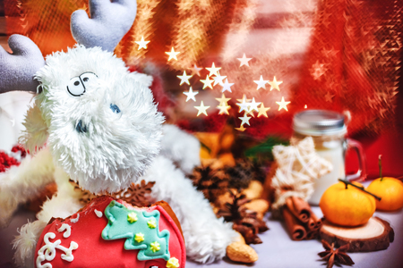 Christmas decor - white toy reindeer with stars in hands, tangerins, cookies and bright star shape bokehの写真素材