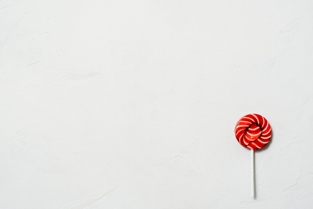 Christmas red lollipop in a white strip on a white marmor backgroundの写真素材