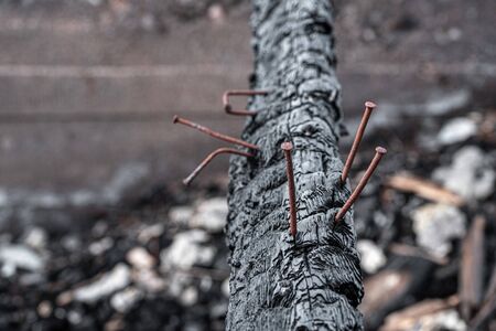The black dirty charred log of the burned-down house with the sticking-out rusty nailsの写真素材