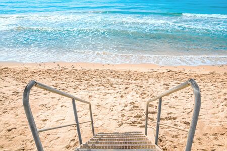 view of steps with a handrail leaders on the clean sandy beach and blue seaの写真素材