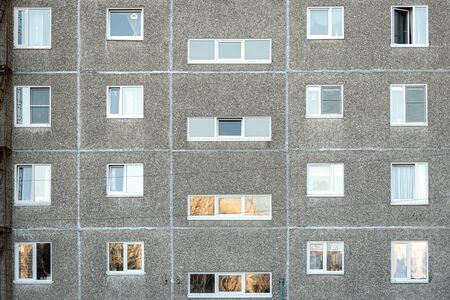 Facade of a grey multi-storey soviet panel building. Russian old urban residential houses with...