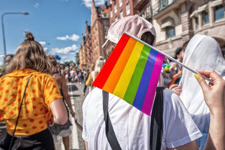 Pride flag in human hand on a LGBTQ pride parade. View from the back.の写真素材
