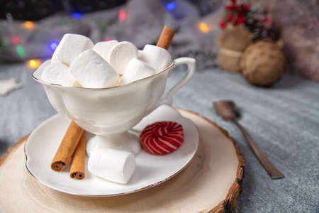 Winter, christmas and new year decoration background with round bokeh garland and cup of coffee with marshmallow on the tableの写真素材