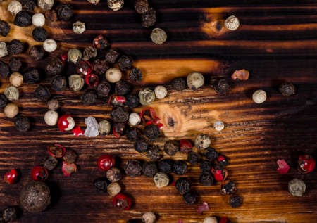 Big red, white and black pepper on a dark burned wooden tableの写真素材