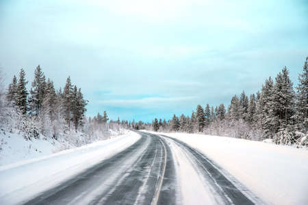 The lonely automobile road in the forest with the snowの写真素材