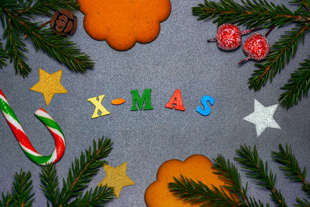 Top view photo of glowing silver christmas decor with pine branches, cones, small stars and gingerbread cookie. X-mas text with color wooden lettersの写真素材