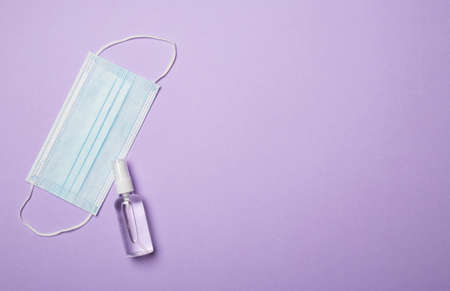 Medical mask and hand sanitizer on color background. Top view, flat lay.の写真素材