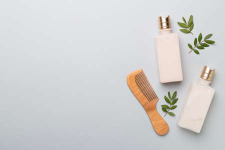 Shampoo and conditioner with herbal extract and comb on color background, top view.の写真素材
