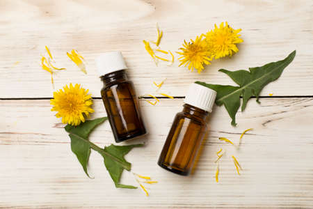 Dandelion essential oil in glass jars on wooden background, top view.の写真素材