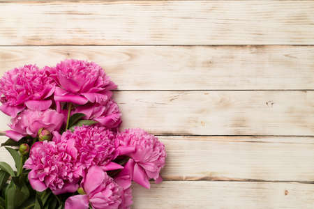 Beautiful pink peony flowers on wooden background, top view.の写真素材