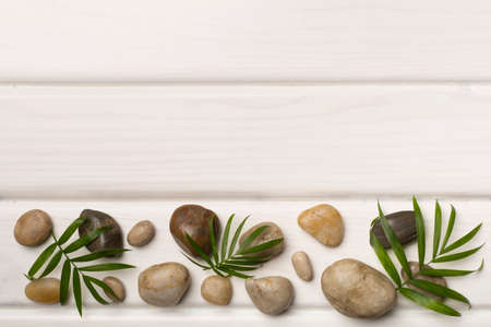 Spa stones and leaves on wooden background, top view.の写真素材