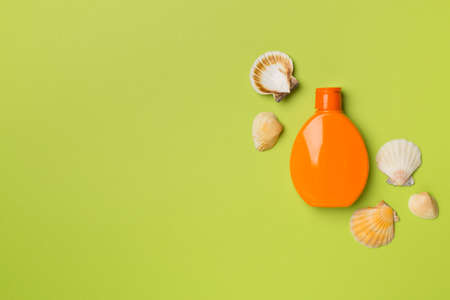 Bottle with sun protection cream and sea shells on color background, top view.の写真素材